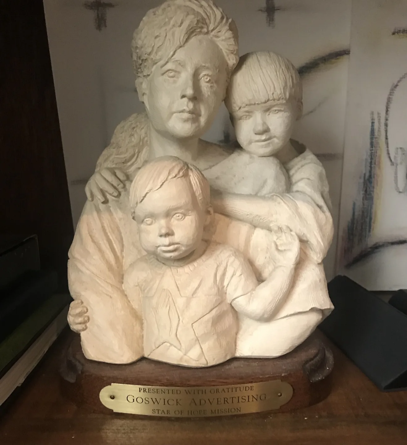 Sculpture of a mother and two children, with a plaque reading Presented with Gratitude, Goswick Advertising, Star of Hope Mission.